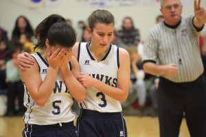 girl basketball player with her face in her hands, teammate tries to comfort her