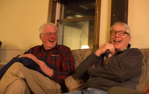 two old men seated on couch laughing