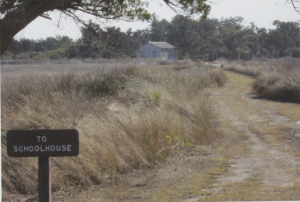 path blazed through field with sign that reads "to schoolhouse"
