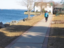 person walking on sidewalk along water