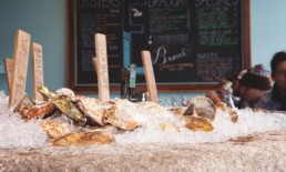 oysters on a bed of ice with a menu board in background