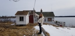 woman pointing at small white building
