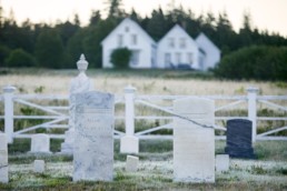 old marble headstones, white house in distance