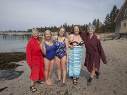 five women posed on a beach after taking a swim