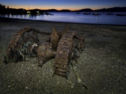 rusty piece of machinery washed up on a beach, photographed at dusk