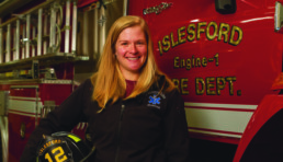 female firefighter posed in front of fire truck
