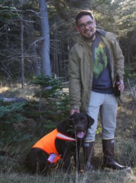 man petting brown dog wearing orange vest