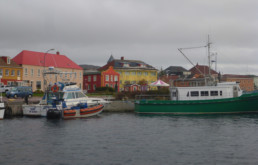 boats docked in front of colorful buildings on cloudy day
